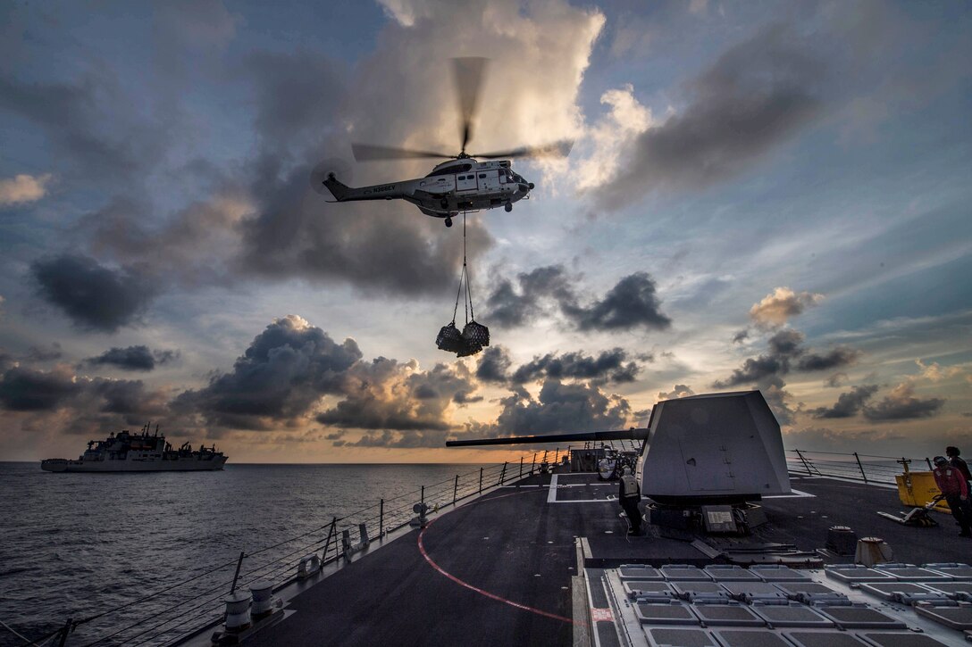 A helicopter delivers supplies to the USS Preble in the Pacific Ocean.