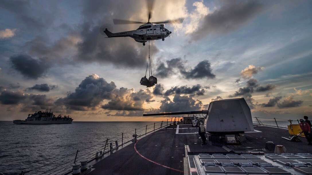 A helicopter delivers supplies to the USS Preble in the Pacific Ocean.