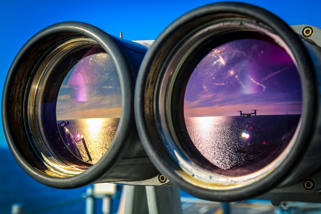 The reflection of an MV-22B Osprey in binoculars aboard the USS Iwo Jima.