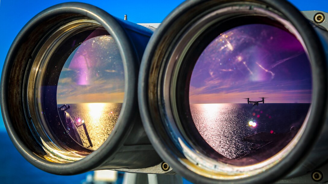 The reflection of an MV-22B Osprey in binoculars aboard the USS Iwo Jima.