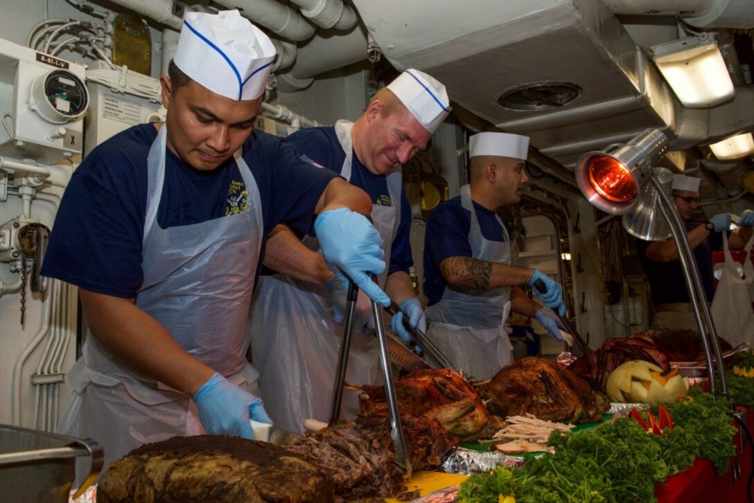 Service members carve turkey.