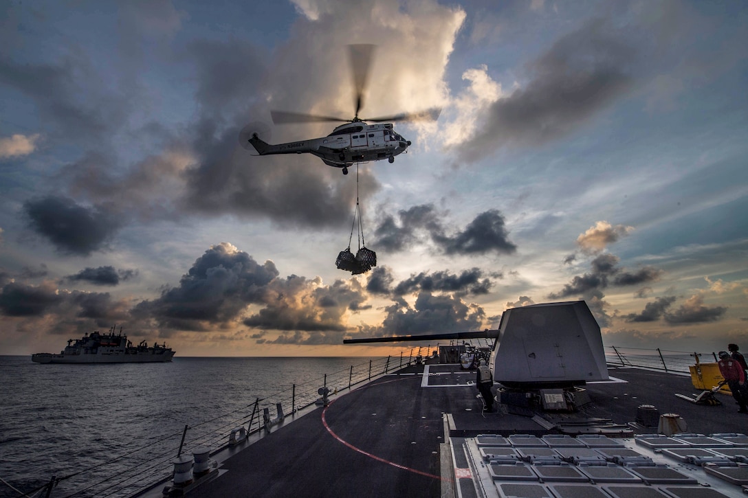 A helicopter delivers supplies to the USS Preble in the Pacific Ocean.