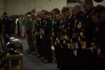 Sailors gather for a memorial service in honor of Aviation Boatswain’s Mate (Equipment) Airman Matthew Chialastri, Lt. Steven Combs and Aviation Ordnanceman Airman Apprentice Bryan Grosso in the hangar bay of the Navy’s forward-deployed aircraft carrier, USS Ronald Reagan (CVN 76). Chialastri, Combs, and Grosso were aboard a C-2A Greyhound from Fleet Logistics Support Squadron (VRC) 30 when it crashed Nov. 22 during a routine transport flight carrying passengers and cargo from Marine Corps Air Station Iwakuni to USS Ronald Reagan.