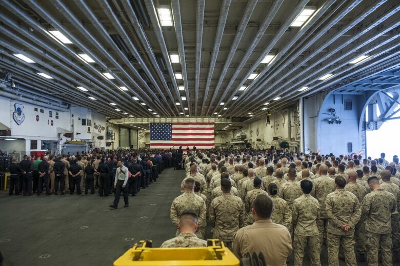 Secretary of the Navy Richard V. Spencer speaks to Sailors and Marines during all hands call in the hangar bay of the amphibious assault ship USS America during his visit on Thanksgiving Day.
