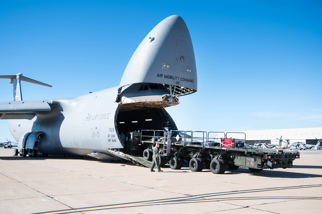 Air Force personnel upload Navy rescue equipment onto a military aircraft.