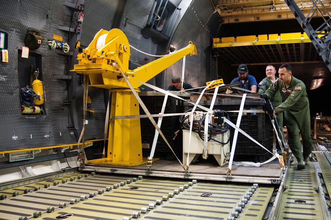 Airmen load Navy undersea rescue equipment onto a military aircraft.