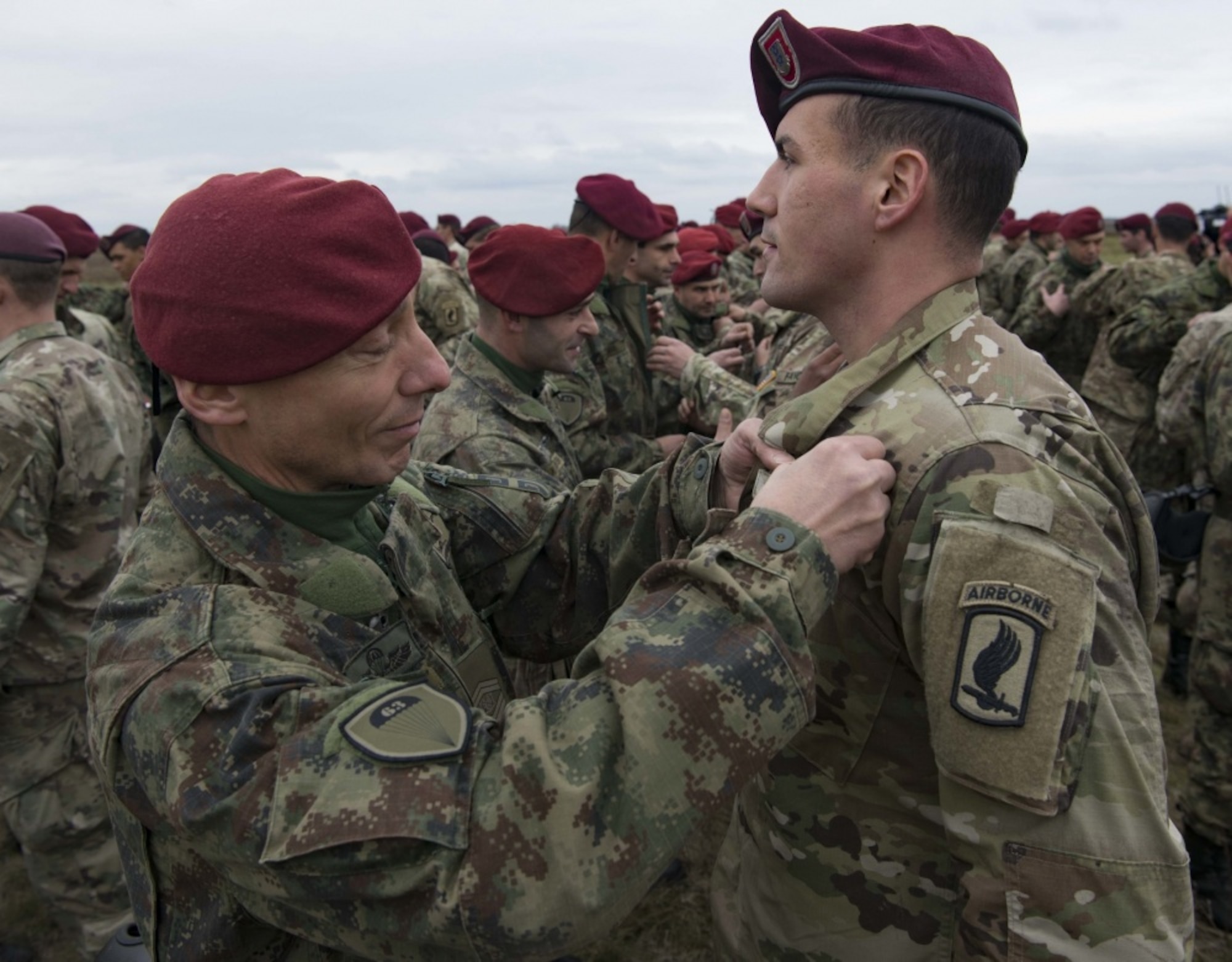 A Serbian paratrooper trades jump wings with a U.S. Army paratrooper assigned to the 173rd Airborne Brigade on Lisicji Jarak Airport, Serbia, Nov. 17, 2017. U.S. and Serbian paratroopers traded jump wings as a symbol of goodwill after conducting five days of airborne insertion exercises together during Exercise Double Eagle. (U.S. Air Force photo by Senior Airman Elizabeth Baker)