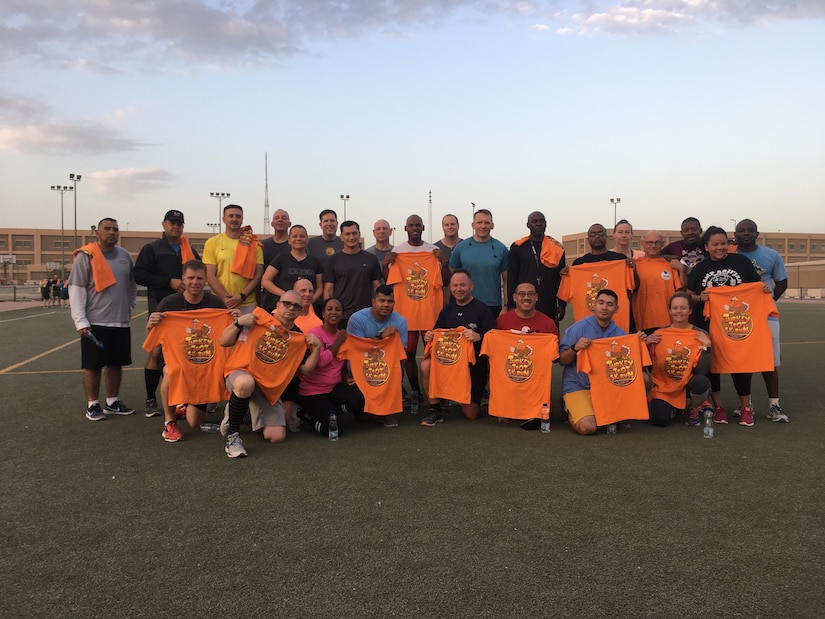 Soldiers pose for a photo holding shirts.