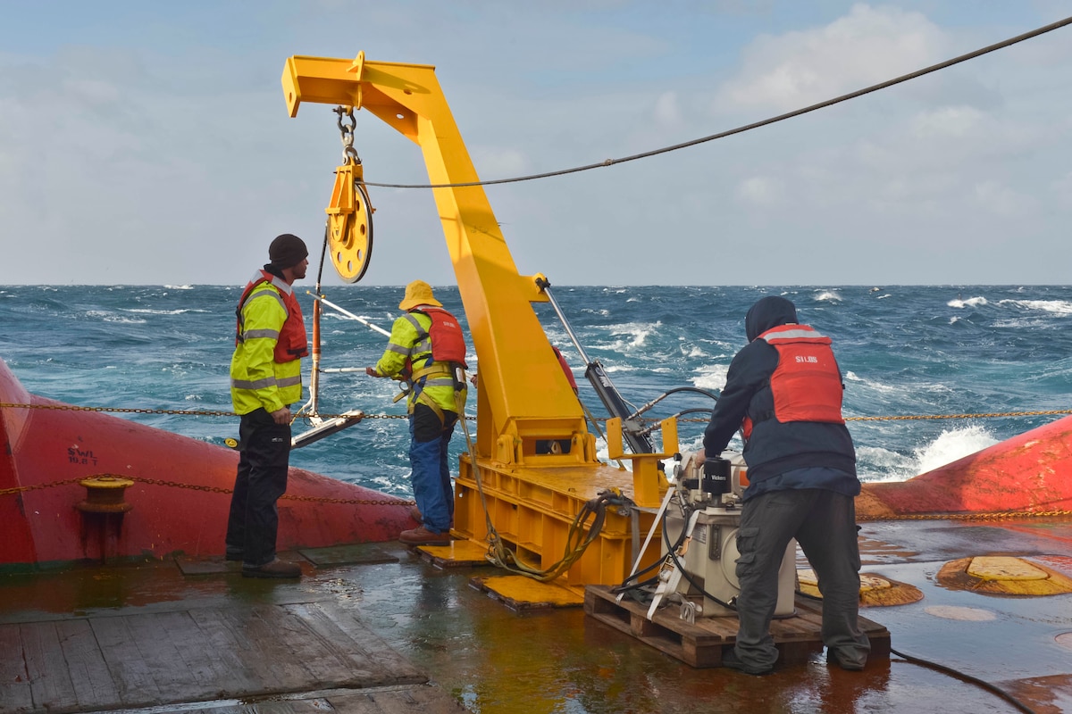 Argentine sailors retrieve side scanning sonar equipment on board a ship.