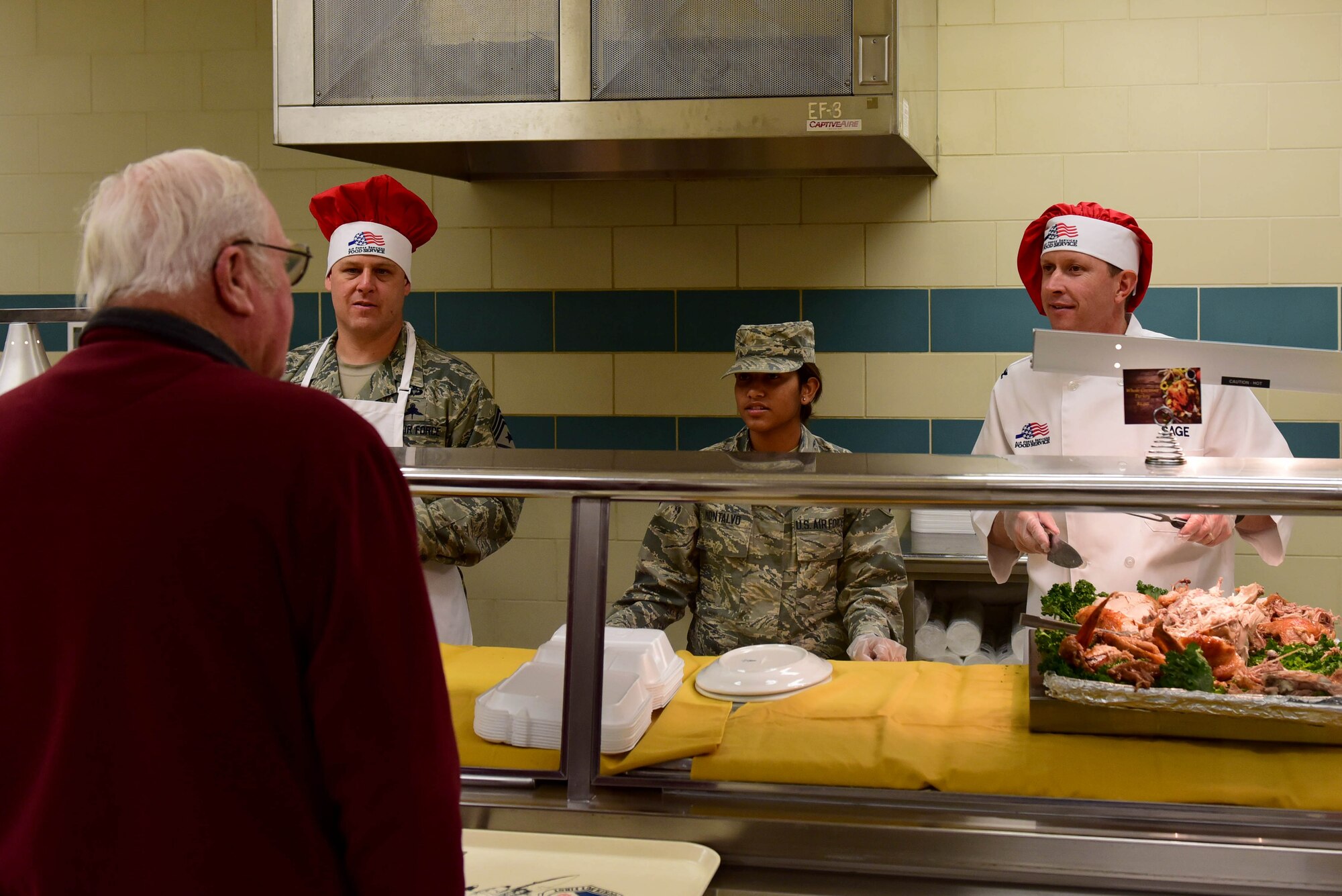 Col. Christopher Sage, 4th Fighter Wing commander, right; Airman 1st Class Kristal Montalvo, 4th Force Support Squadron food service worker, center and Chief Master Sgt. William Adams, 4th FW command chief, left, help serve a Thanksgiving holiday meal to Airmen and dining facility attendees at the Seymour Johnson Air Force Base 4th FSS dining facility Nov. 23, 2017, at Seymour Johnson AFB, North Carolina. Base leaders helped serve more than 150 meals to dining facility guests on Thanksgiving Day.  (U.S. Air Force photo by Airman 1st Class Kenneth Boyton)