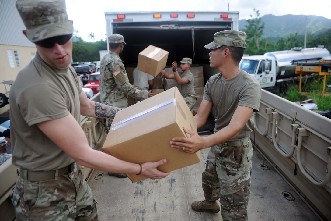 Soldiers unload trucks with food and water for residents.