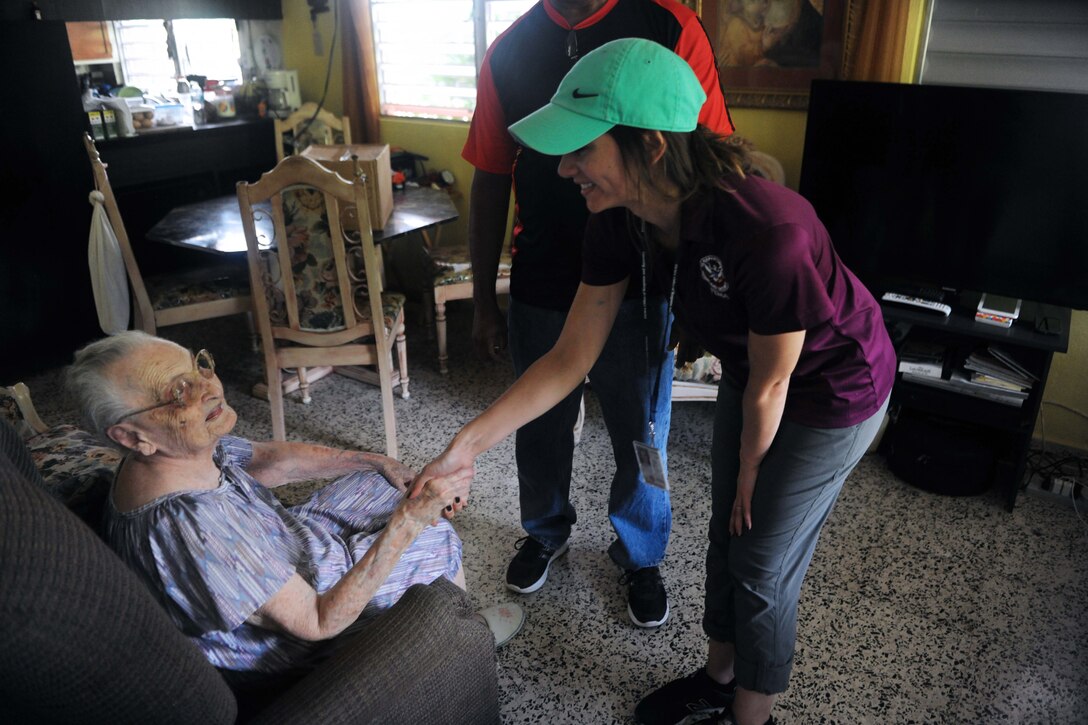 FEMA worker greets resident while delivering water and food.