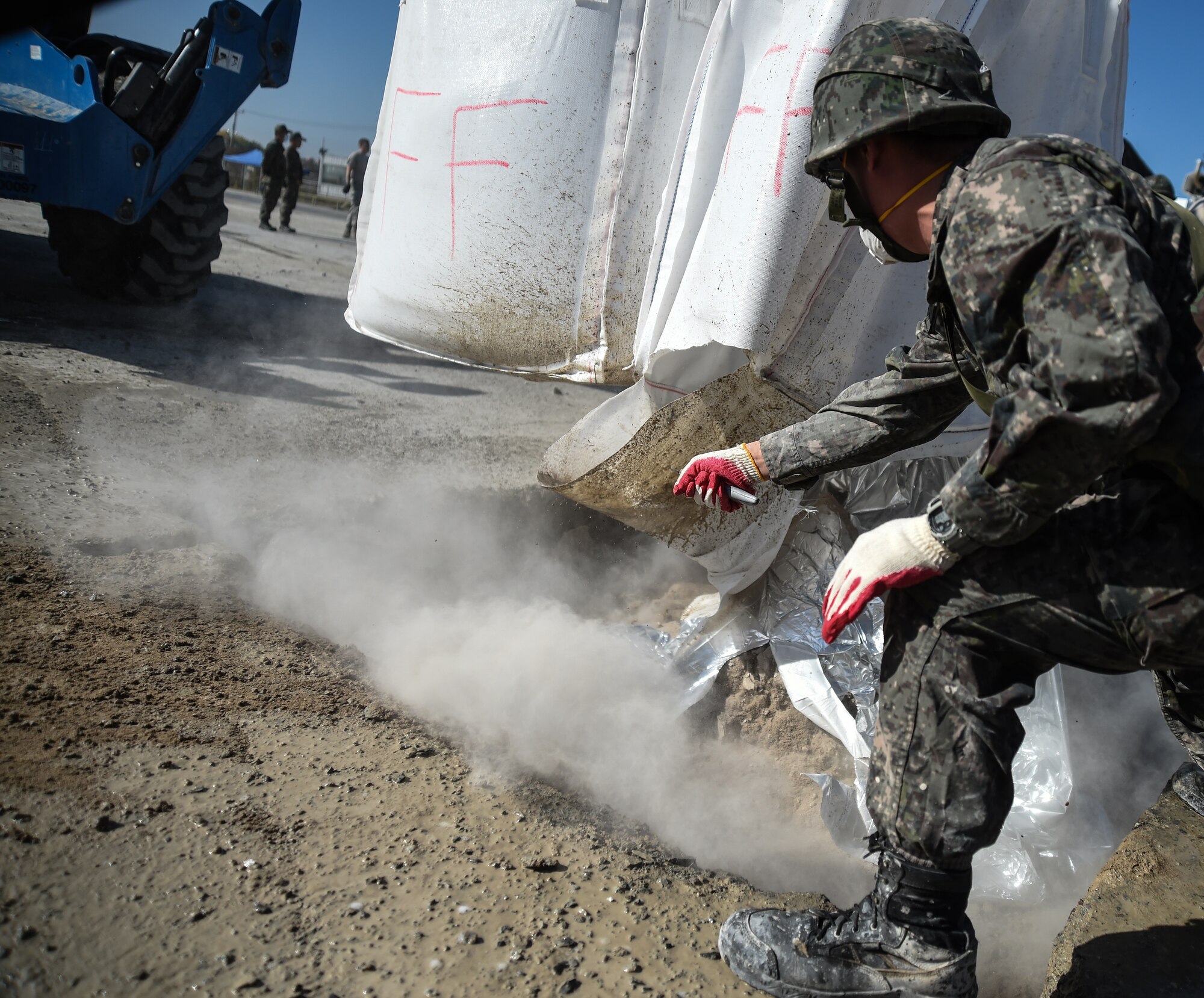 Republic of Korea Air Force Senior Airman Jinguk Kim, civilian engineer electrician, slices open a bag of quick-set concrete during a Rapid Airfield Damage Repair bilateral training exercise at Gwangju Air Base, Republic of Korea, Nov. 9, 2017. Similar to an assembly line, RADR systematically lines up civil engineer personnel and equipment to quickly repair a runway after attack. The training exercise was designed to enhance interoperability, prepare for wartime contingencies and strengthen partnerships in the Indo-Asia Pacific region. (U.S. Air Force photo by Senior Airman Curt Beach)
