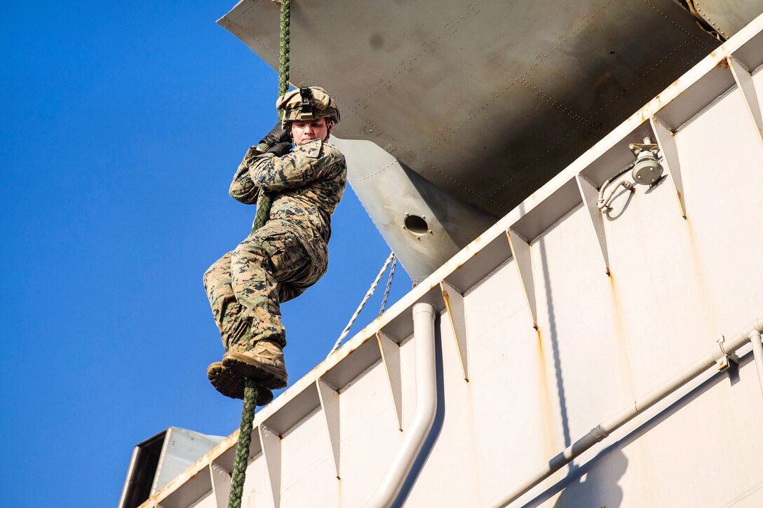 A Marine descends from an MV-22B Osprey during fast-rope training.