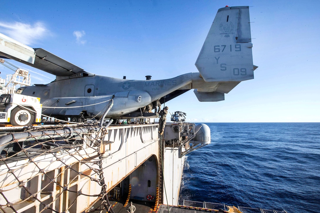 A Marine descends from the tail door of an MV-22B Osprey during fast-rope training.