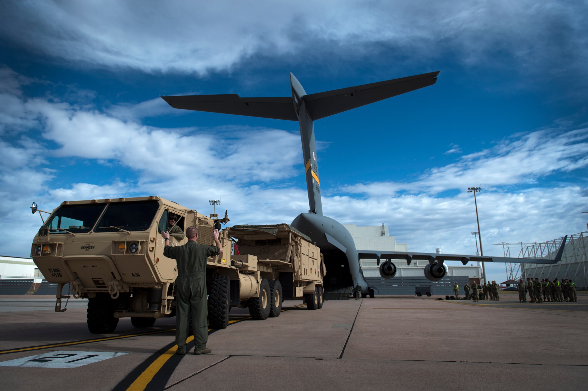 U.S. Air Force Tech. Sgt. Jerry Daniels, a loadmaster instructor with the 58th Airlift Squadron, directs a U.S. Army Soldier assigned to the 4th Battalion 3rd Air Defense Artillery Regiment, while he backs a vehicle onto a C-17 Globemaster III