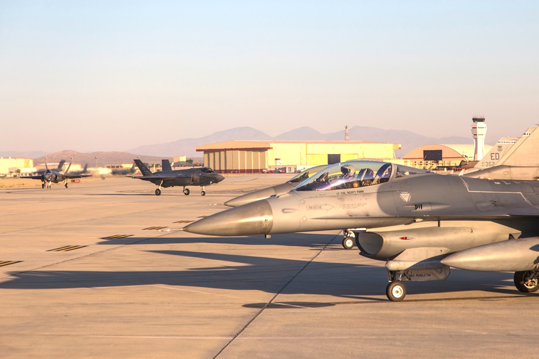 F-35s and F-16s taxi to the end of the runway at Edwards Air Force Base for for a multiple aircraft test event called Orange Flag. The test aircraft, outfitted with data-gathering gear, launched from Edwards Air Force Base, Naval Air Weapons Station China Lake, Naval Air Station Point Mugu, and Nellis AFB, Nevada.
 Orange Flag tests the interoperability of the Air Force, Navy and Marine fighters, bombers, and Command-and-Control aircraft. 
(Photo by Darin Russel/Lockheed Martin)