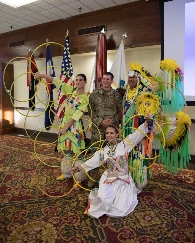 A soldier poses for a photo with Native American dancers