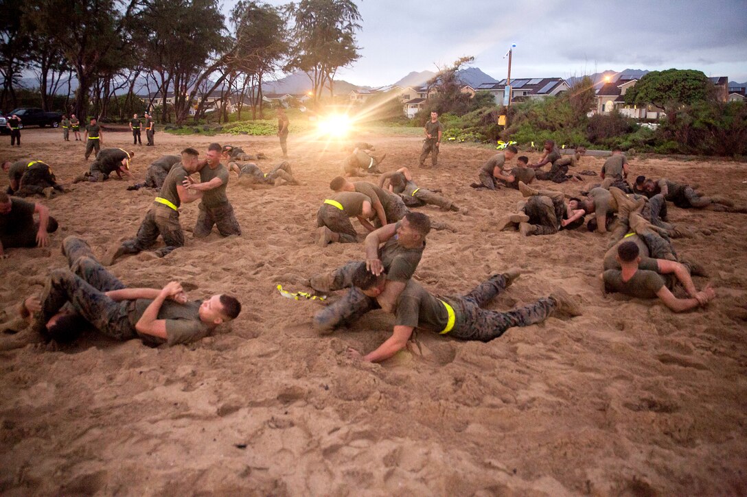 Marines practice hand to hand fighting on a beach.