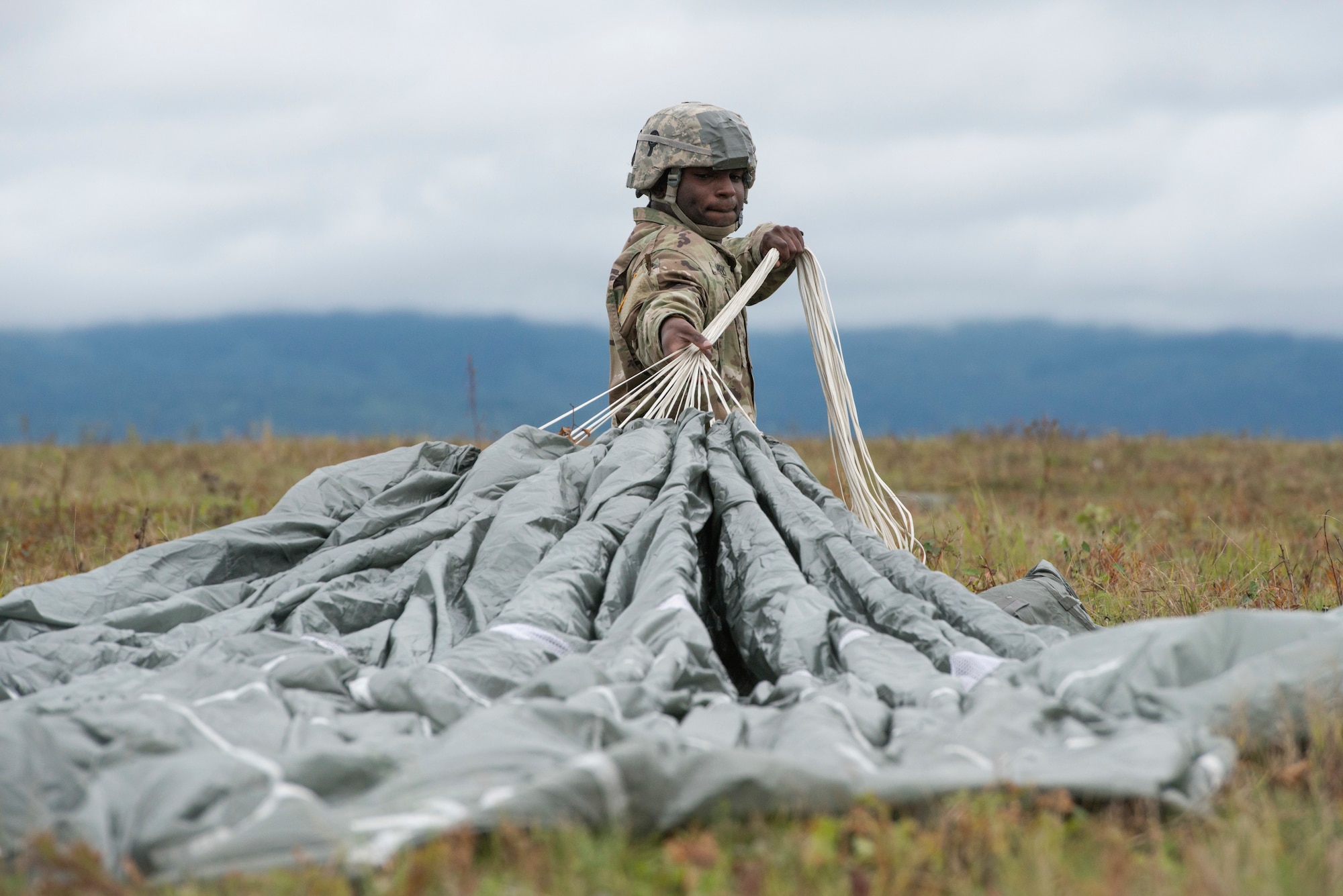 A paratrooper assigned to 2nd Battalion, 377th Parachute Field Artillery Regiment, 4th Infantry Brigade Combat Team (Airborne), 25th Infantry Division, U.S. Army Alaska, recovers his parachute after conducting airborne jump training at Malemute drop zone, Joint Base Elmendorf-Richardson, Alaska, Aug. 24, 2017.
