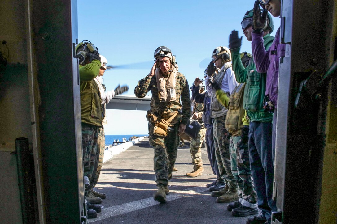 The commander of U.S. Africa Command salutes sideboys as he arrives on a ship.