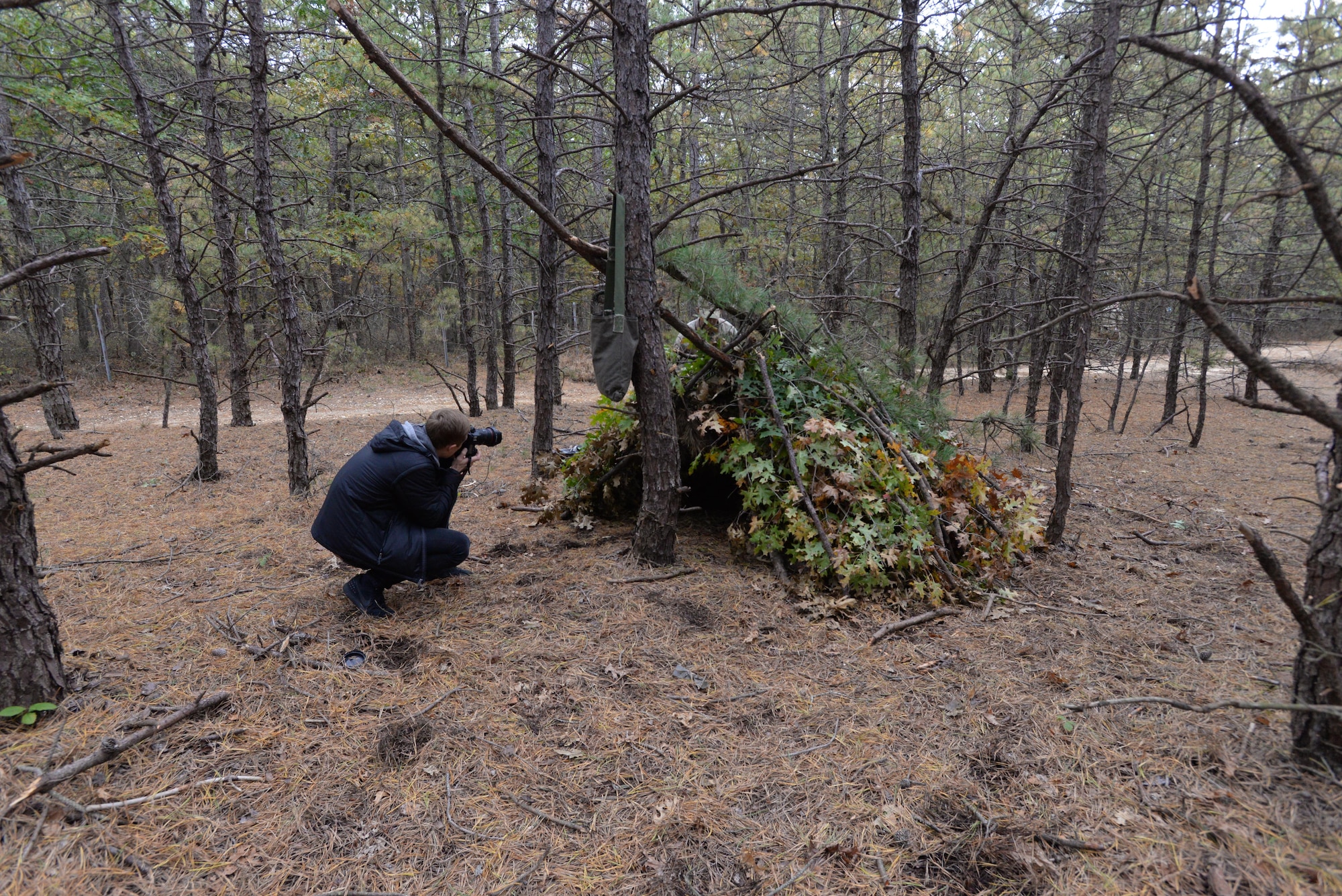 Jeff Allen, a Futures Magazine photographer, takes a photo of Senior Airman Alexander Triani, a pararescueman with the 103rd Rescue Squadron of the 106th Rescue Wing assigned to the New York Air National Guard, during basic survival training in the woods of Westhampton Beach, New York November 1, 2017.