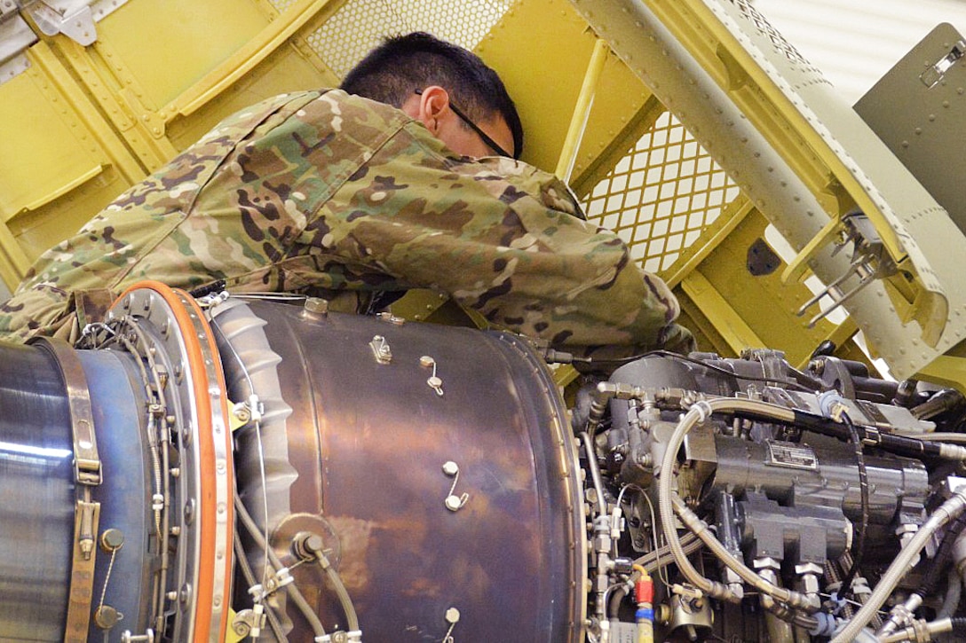 A soldier inspects a CH-47 Chinook helicopter for corrosion.