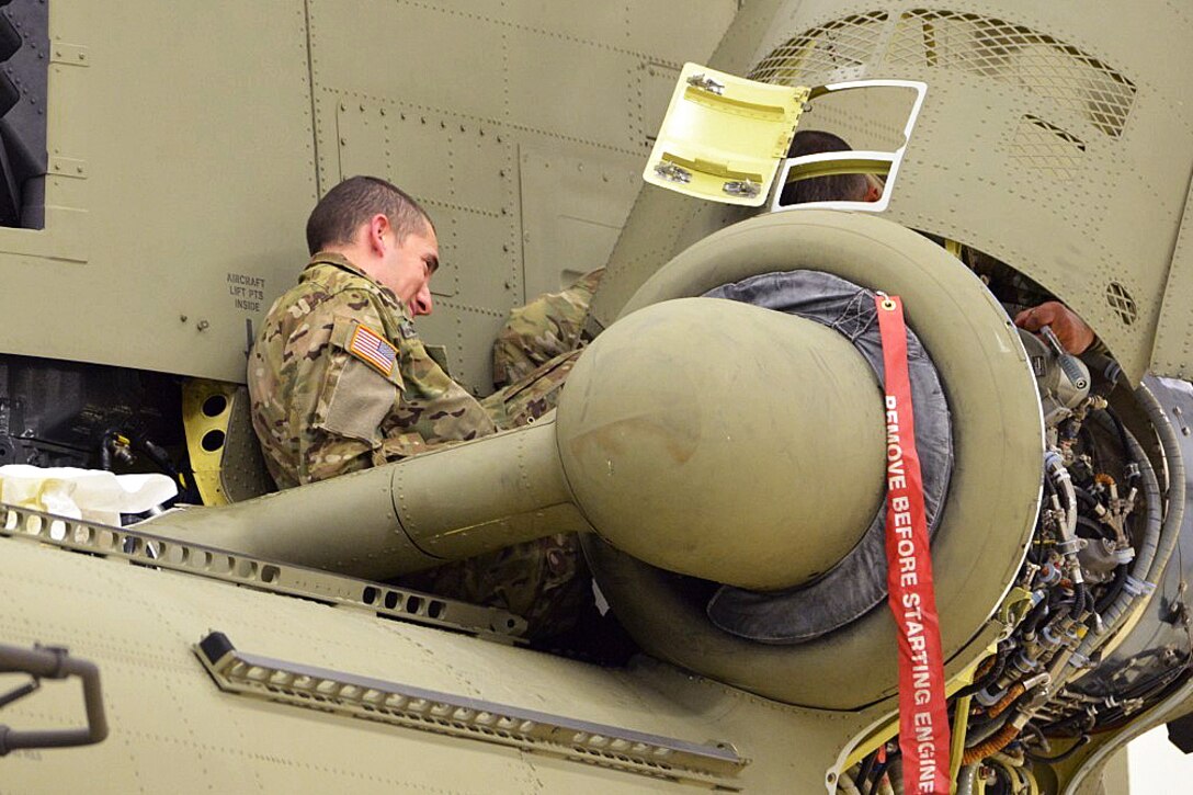 Soldiers inspect a CH-47 Chinook helicopter for corrosion