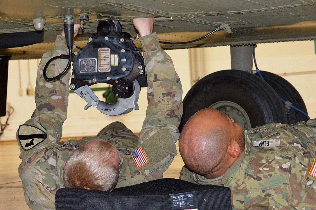 Soldiers inspect a CH-47 Chinook helicopter for corrosion