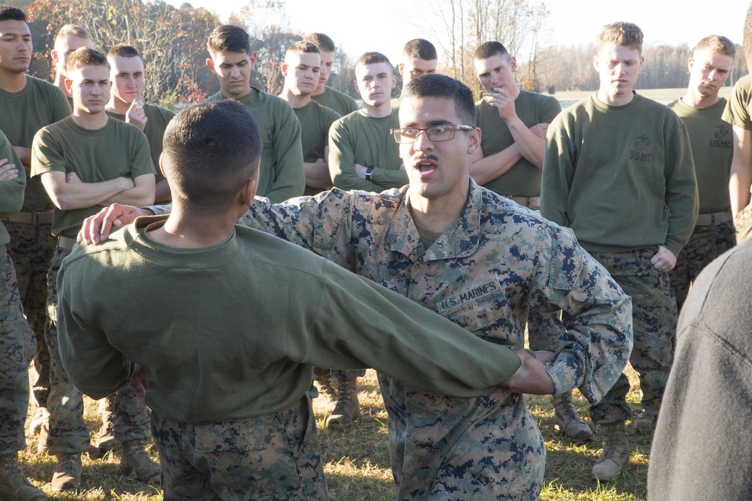 Sgt. Brandon Bedard, instructor, Basic Security Guard Course, Training Co., U.S. Marine Corps Security Forces Regiment, demonstrates a self-defense takedown to students in Class 2-18 during a field exercise at Naval Support Activity Northwest Annex, Chesapeake, Va., Nov. 28. Marines had to demonstrate arm bars, baton defense tactics, and leg sweeps among others in order to show proficiency in Marine Corps Martial Arts skills based on their belt level. (Official U.S. Marine Corps photo by Chris Jones/Released)