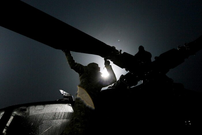 A soldier climbs on a helicopter.