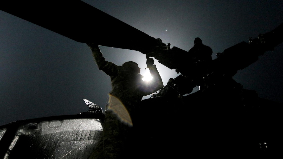A soldier climbs on a helicopter.