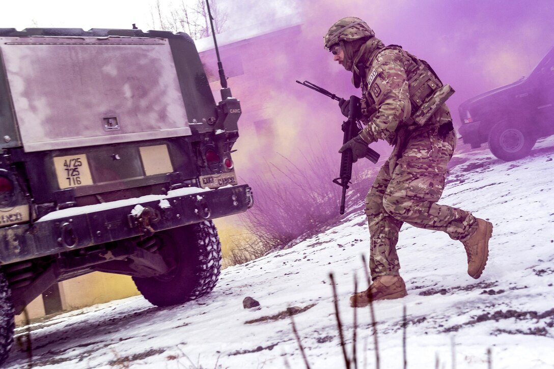 A soldier runs towards a vehicle with purple smoke in the air.