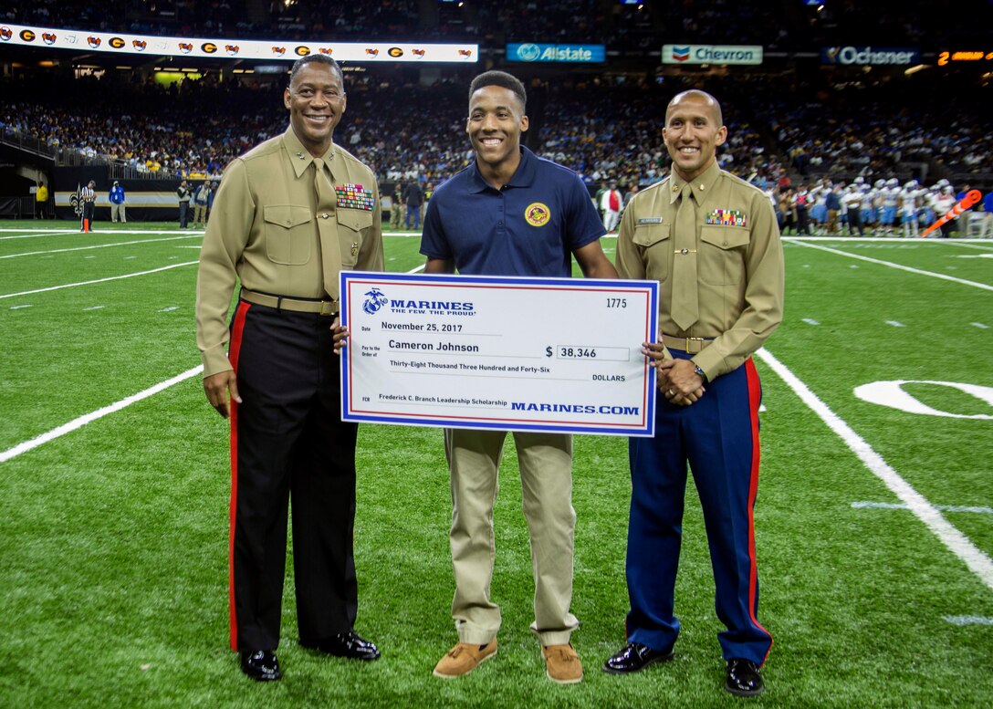 Major General Craig C. Crenshaw, Commanding General of Marine Corps Logistics Command, left, and Maj. William T. Kerrigan, Commanding Officer of Recruiting Station Baton Rouge, present Cameron Johnson, a student at Southern University, the Frederick C. Branch Leadership Scholarship check during the Bayou Classic football game at the Mercedes-Benz Superdome in New Orleans, LA, Nov. 25, 2017. The scholarship is presented to students who display exemplary leadership and academic achievement. The Bayou Classic offered the Marine Corps the opportunity to showcase the importance of music through sponsorship. (U.S. Marine Corps photo by Lance Cpl. Jack A. E. Rigsby/Released)