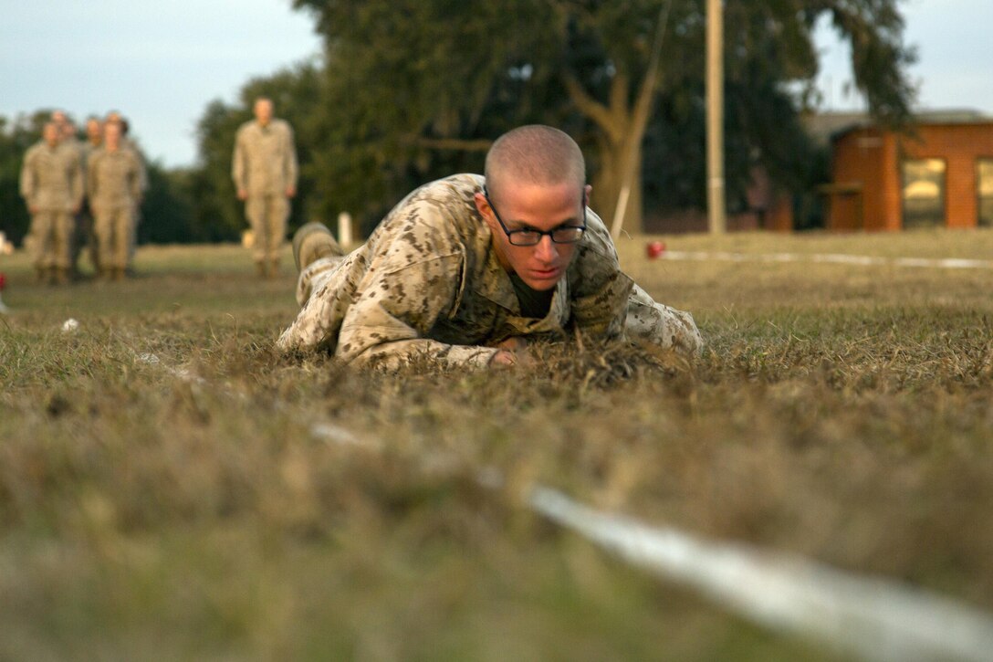 A Marine recruit performs a low crawl.