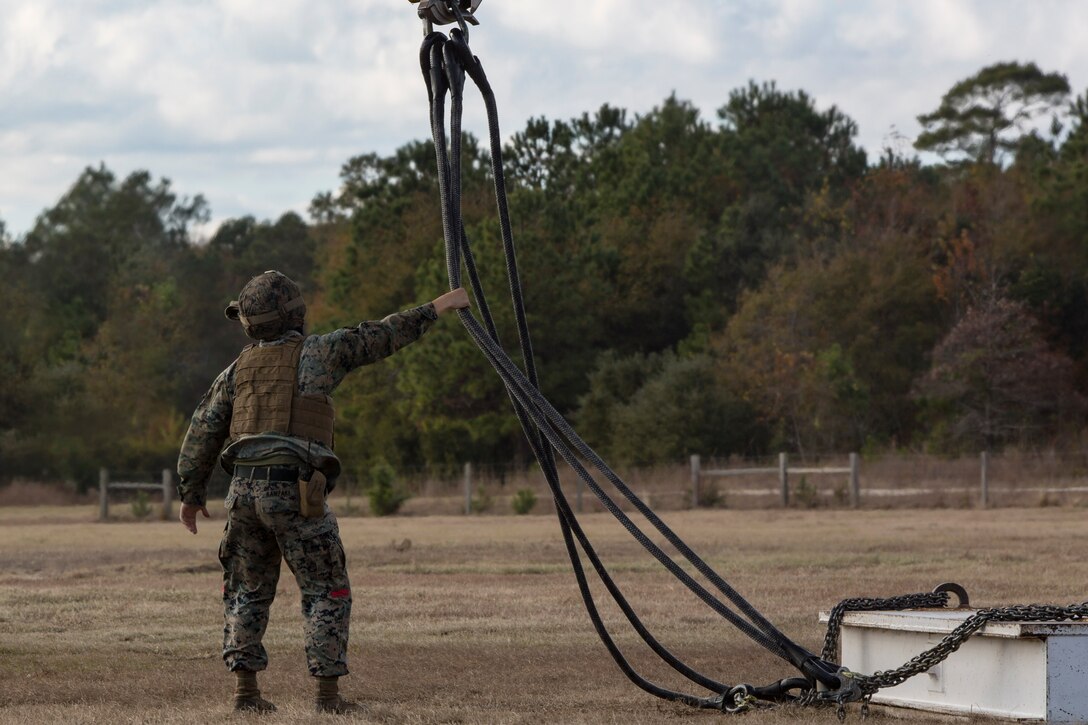 Cpl. James Kanzaki, a landing support specialist with Combat Logistics Battalion 6, 2nd Marine Logistics Group guides cables while a CH-53E Super Stallion lifts practice materials during Helicopter Support Team training at Camp Lejeune, N.C., Nov. 28, 2017. A Helicopter Support Team is comprised of approximately eight landing support specialist Marines who ensure the equipment is properly attached and secured before pilots transport the gear or supplies to their destination. (U.S. Marine Corps photo by Cpl. Aaron Henson)