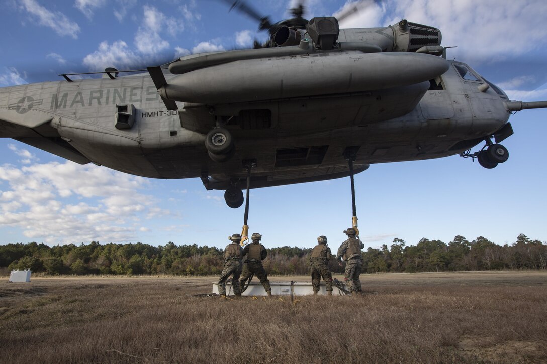 Marines with Combat Logistics Battalion 6, 2nd Marine Logistics Group attach cables and practice materials to a CH-53E Super Stallion during Helicopter Support Team training at Camp Lejeune, N.C., Nov. 28, 2017. A Helicopter Support Team is comprised of approximately eight landing support specialist Marines who ensure the equipment is properly attached and secured before pilots transport the gear or supplies to their destination. (U.S. Marine Corps photo by Cpl. Aaron Henson)