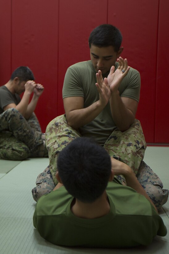 CAMP KINSER, OKINAWA, Japan— Cpl. Emmanuel Guzman teaches a member of the Japan Ground Self-Defense how to execute an arm bar from the mount during a Marine Corps Martial Arts Program demonstration Nov. 27 aboard Camp Kinser, Okinawa, Japan.