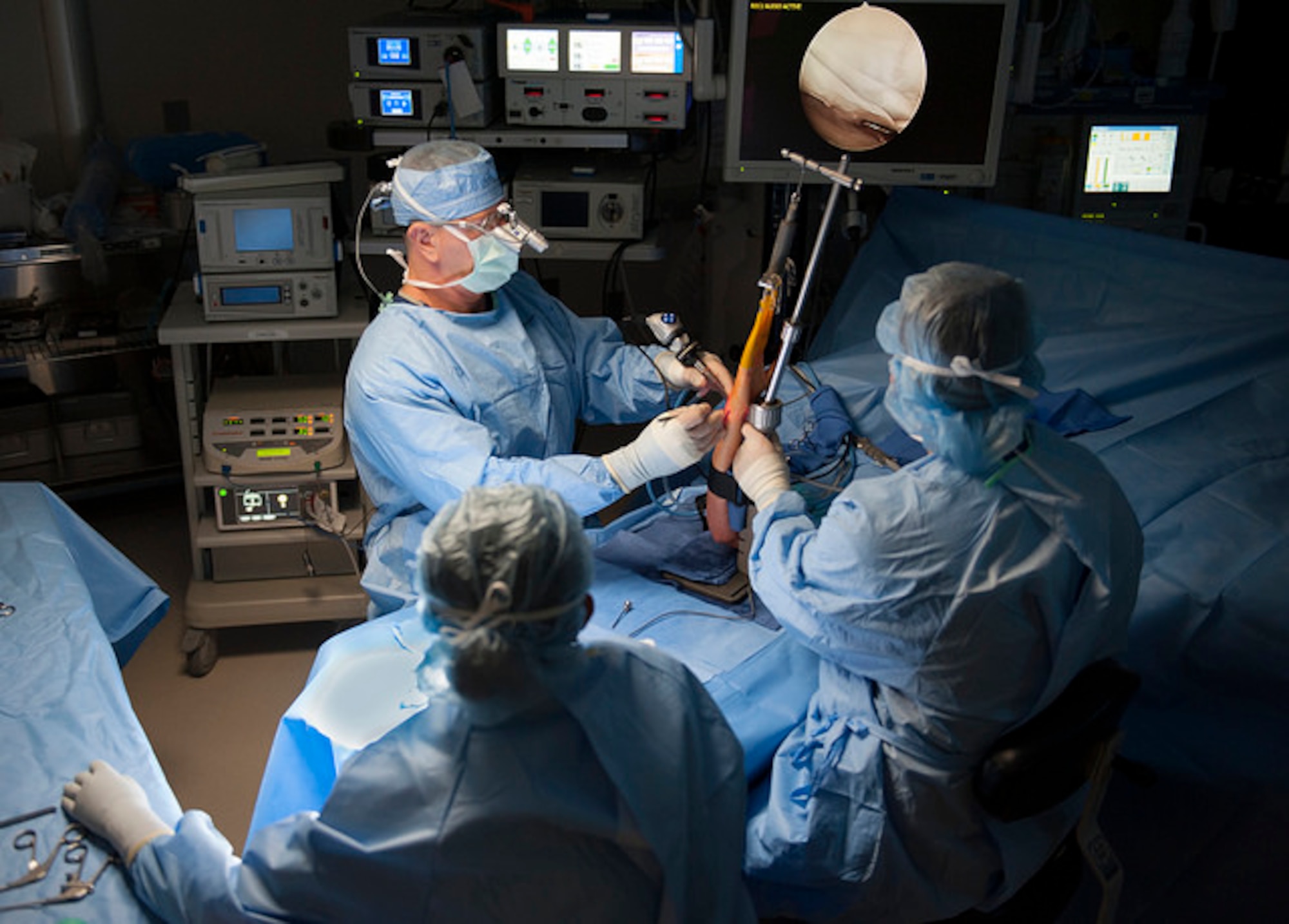 Lt. Col Dana Hess (left), a surgeon with the 60th Surgical Operations Squadron, David Grant U.S. Air Force Medical Center, conducts a right ulna resection arthroscopy on a patient, Aug. 31, 2017, Travis Air Force Base, Calif. Responsible for assisting Hess during the operation, Staff. Sgt. Scot Butler (right) and Airmen Alyssa Avelino (center), 60 SGCS, surgical service specialists, ensure that the procedure goes as smoothly as possible.(U.S. Air Force photo/ Heide Couch)