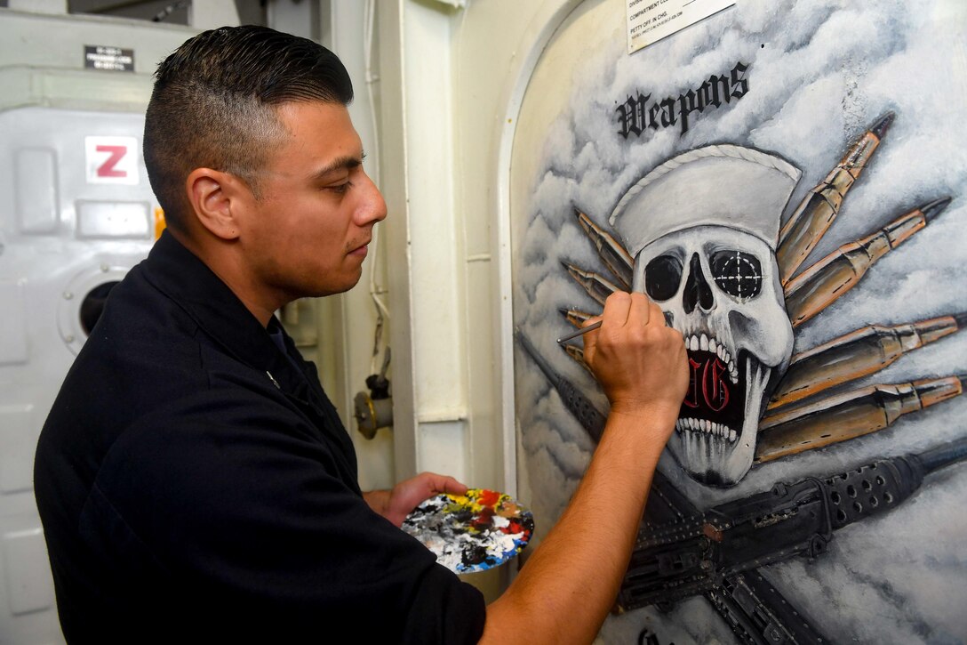 A sailor works on a painting.