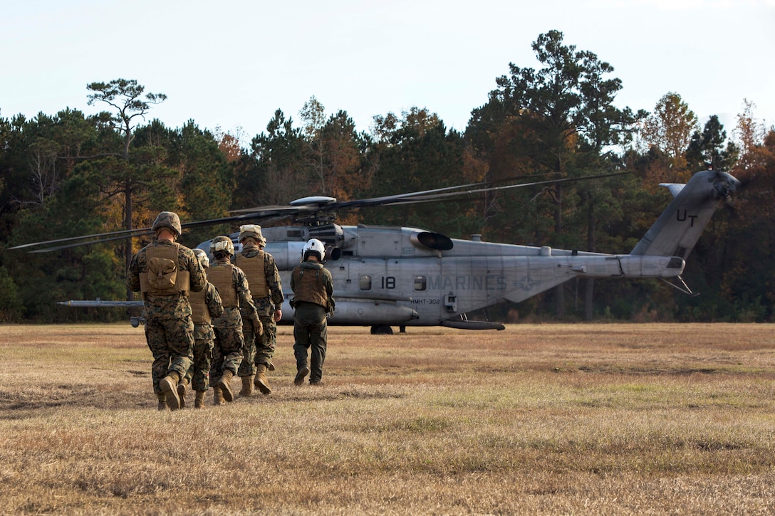 Marines walk toward a CH-53E Super Stallion helicopter before participating in hoist training.