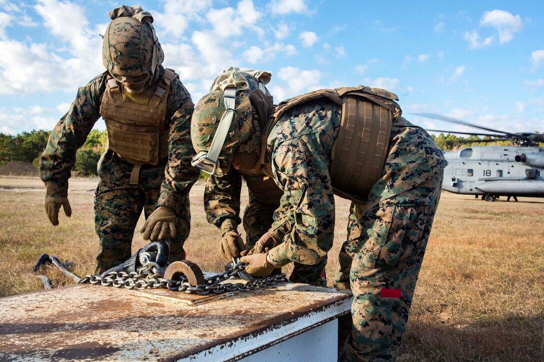 Marines ensure cables are properly attached to practice materials before participating in hoist training.