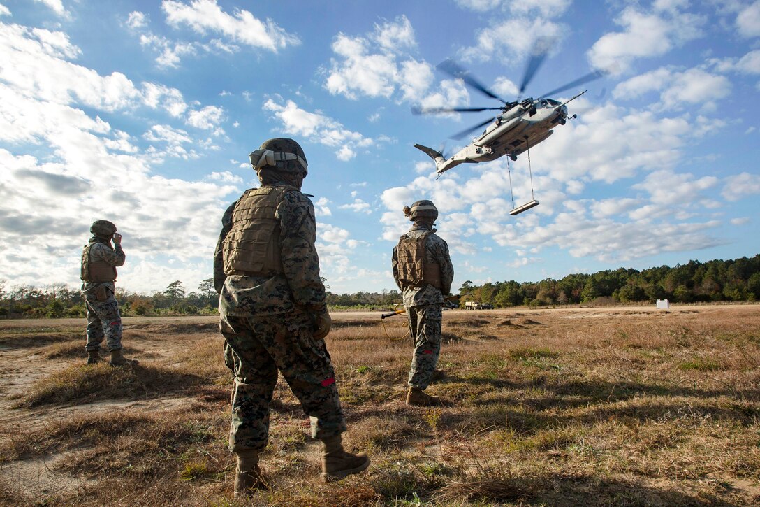 Marines observe a CH-53E Super Stallion helicopter lifting off during hoist training, part of helicopter support team training.