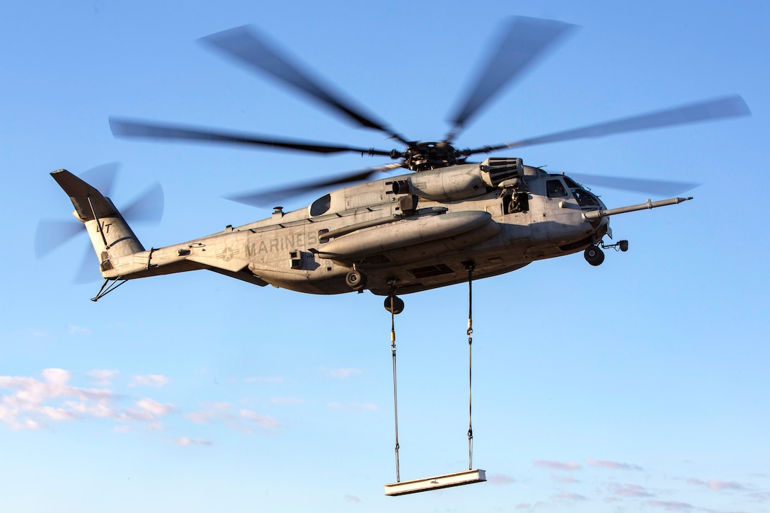 A CH-53E Super Stallion helicopter transports practice materials during hoist training.