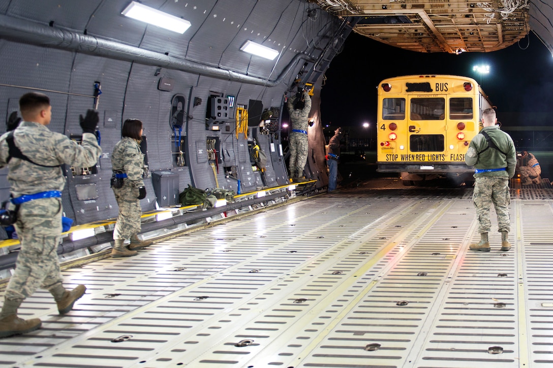 Airmen load buses onto a C-5M Super Galaxy aircraft at Travis Air Force Base, Calif.
