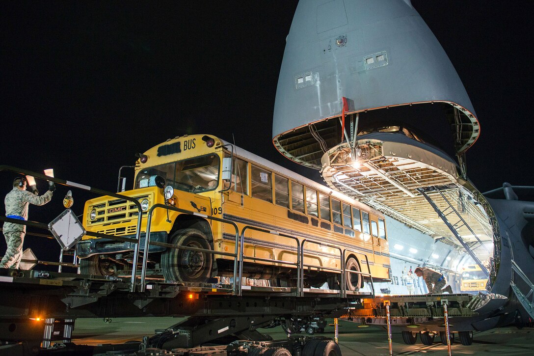 Airmen load a bus onto a C-5M Super Galaxy aircraft at Travis Air Force Base, Calif.