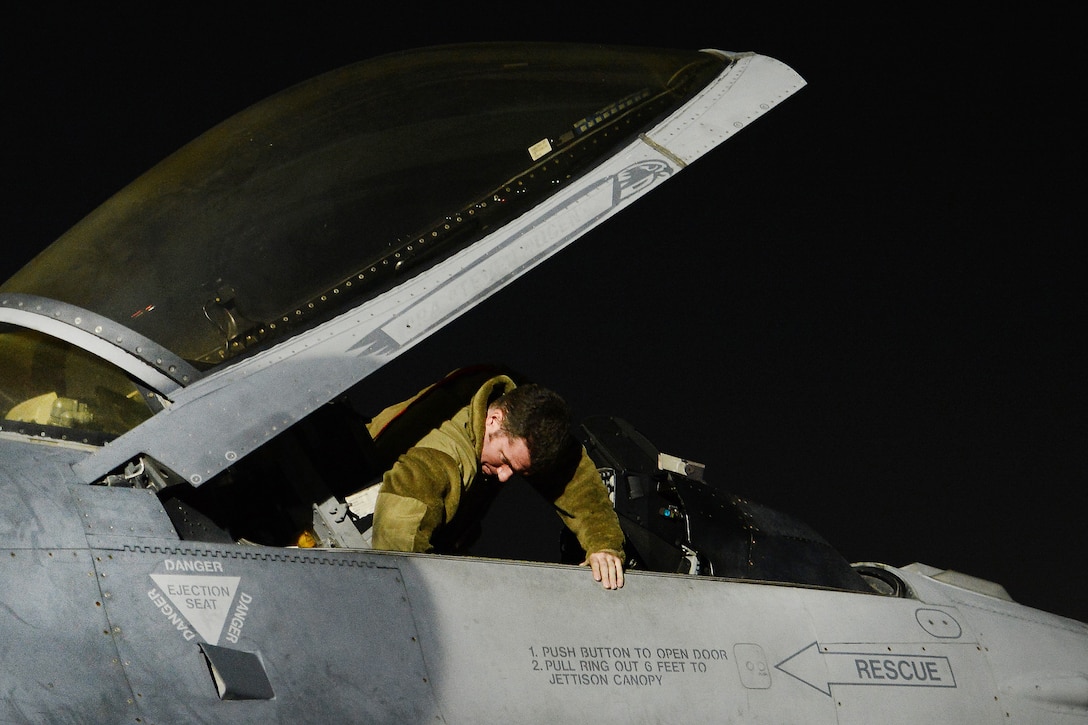 An airman prepares the cockpit of an F-16 Fighting Falcon before takeoff.