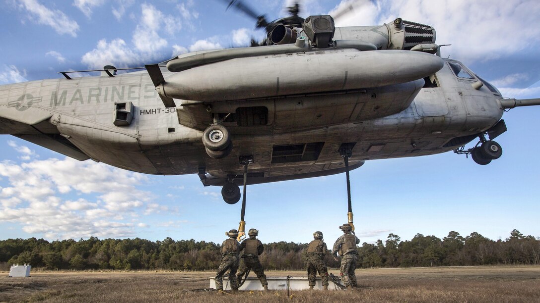 Marines attach cable to a helicopter during training.