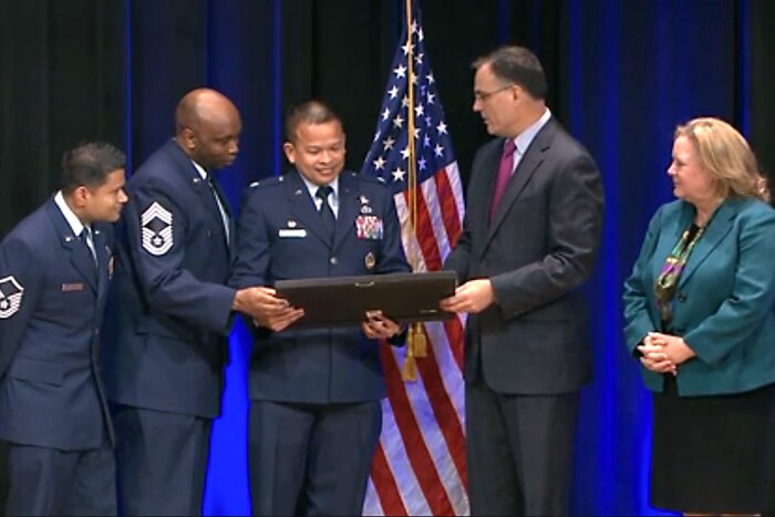 A group of people stand on stage holding an award.