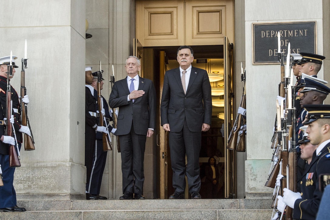 Defense Secretary Jim Mattis and the Libyan prime minister stand at a Pentagon entrance, flanked by honor guard members.